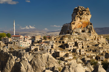 Fototapeta premium View of Ortasihar rock Castle with minaret Mount Erciyes and fairy chimneys Cappadocia Turkey