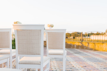 Three white classic chairs with beige upholstery at an off-site wedding ceremony. Copying space