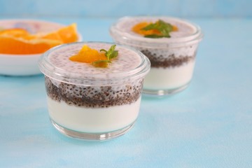 Healthy bowls of yogurt or curd and Chia seeds, topped with chopped oranges and mint leaves. Chia seeds pudding dessert.
