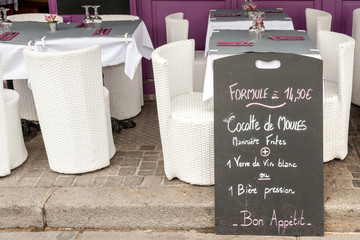 Menu display with mussels specials along outside tables in Honfleur seafood restaurant, Normandy, France
