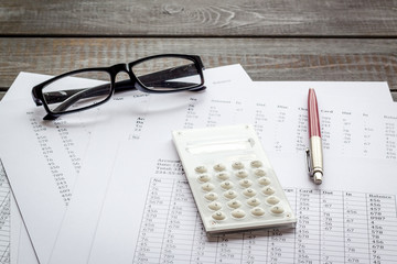 Taxes calculation concept. Financial documents, calculator, glasses on dark wooden background