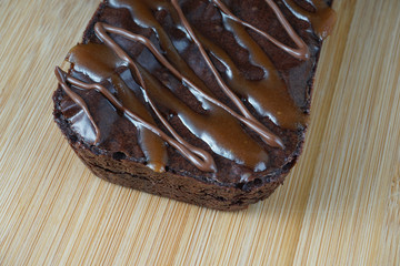 Close up of a moist dark chocolate brownie over chopping board.