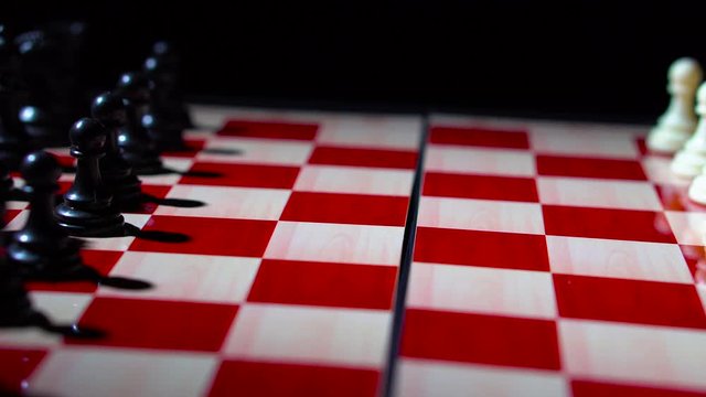 Closeup track shot of chessboard and chess pieces from black to white with white move e4 played - 4K