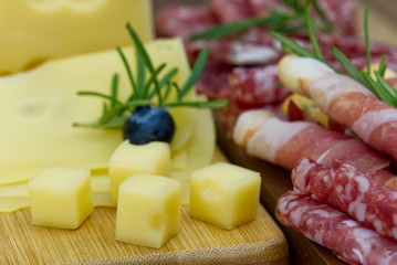 Beautiful sliced food arrangement close-up photo. Italian style antipasto plate, cheese, ham, salami, rosmarin, prosciutto
