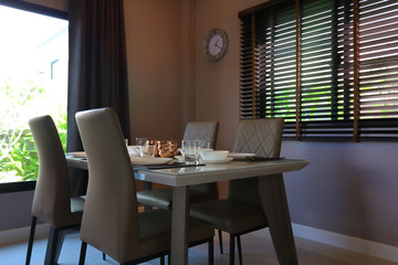 dish ware sets arrange on dining table inside eating room of modern home interior with green garden outside view the window