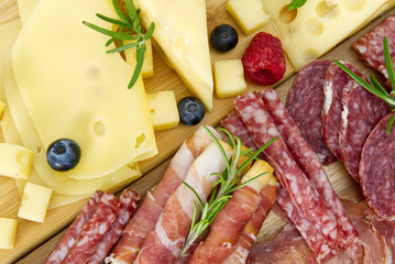 Beautiful sliced food arrangement close-up photo. Italian style antipasto plate, cheese, ham,...