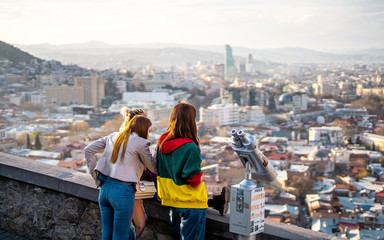 3 teenagers looking at the view of Tbilisi from Narikala Fortress before sunset , Tbilisi , Georgia