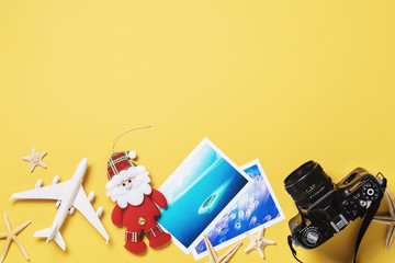 Toy airplane, photos and camera on a yellow background with copy space. Christmas Travel Planning Concept