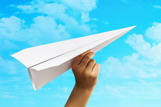 A child launches a paper plane into the sky. Concept on opening a new business and striving forward