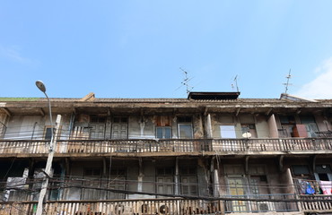 Outside view of vintage building with blue sky background, the building has peeled wall and wooden doors with long balcony