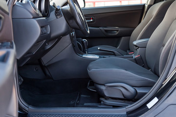 Comfortable front seats inside the car: the driver and passenger, tied with genuine black leather, modern interior design, the steering wheel covered with black wood and a luxurious center console.