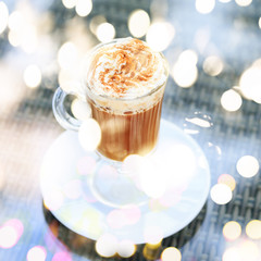 Irish coffee in an outdoor bar. Concept of St Patrick holiday. Holiday background. Irish national day. Warm tone. Square with festive bokeh lights