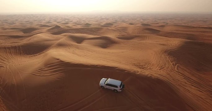 Aerial view of 4x4 off road land vehicle taking tourists on desert dune bashing safari in Dubai, UAE