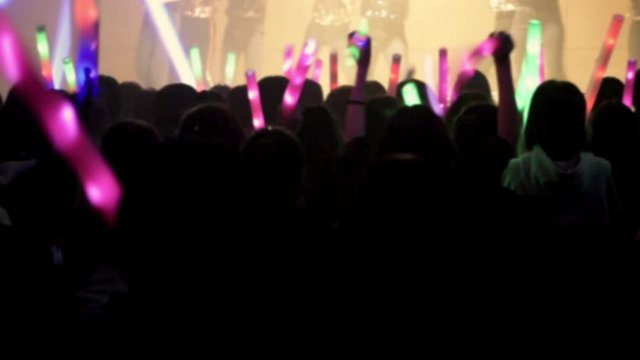 The silhouette of a cheering audience as they watch the performance dynamically in the concert. Defocused concept.