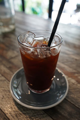 Close up glass of iced black coffee on wooden table