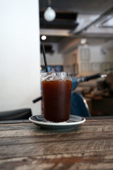 Close up glass of iced black coffee on wooden table
