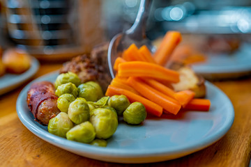 Selective focus and close up of an unidentifiable chef plating up a traditional roast dinner