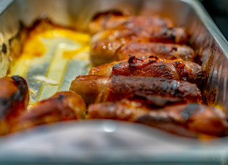  Selective focus and close up of pigs in blankets, sausage wrapped in bacon, in an aluminium foil tray