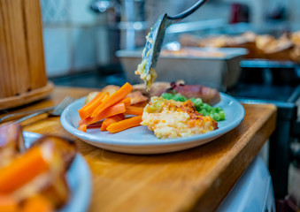 Close up of unidentifiable chef plating up a traditional roast dinner