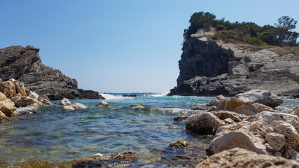 Panoramic view of pebble beach with clear azure blue water and layered rocks, beautiful mediterranean Adriatic Sea coast, Montenegro