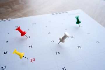 Thumbtack a date on calendar on the table with wooden background, concept for important date,...
