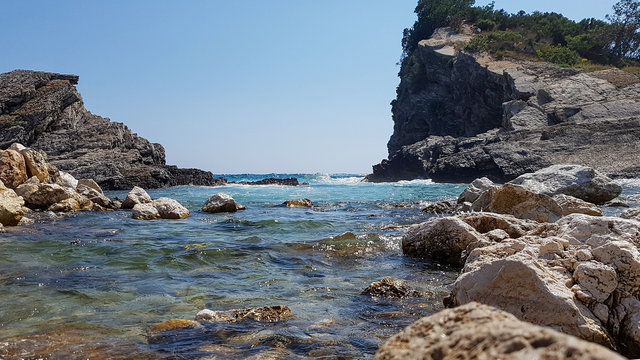 Panoramic view of pebble beach with clear azure blue water and layered rocks, beautiful mediterranean Adriatic Sea coast, Montenegro