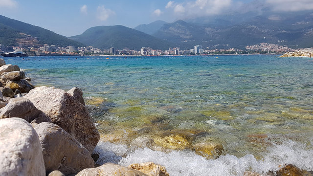 Panoramic view of pebble beach with clear azure blue water and layered rocks, beautiful sea landscape with picturesque sea and horizon line, Montenegro