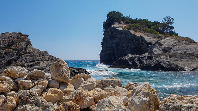 Panoramic view of pebble beach with clear azure blue water and layered rocks, beautiful sea landscape with picturesque sea and horizon line, Montenegro