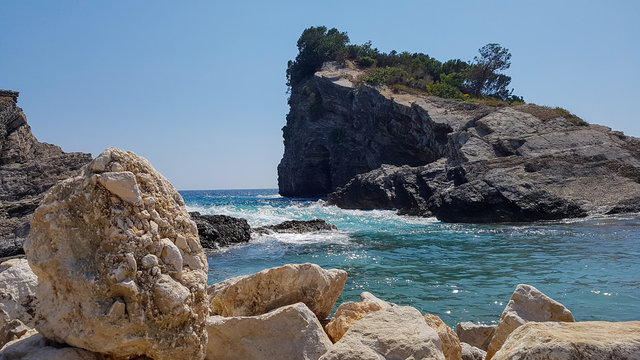 Panoramic view of pebble beach with clear azure blue water and layered rocks, beautiful sea landscape with picturesque sea and horizon line, Montenegro