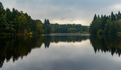 Fototapeta na wymiar reflections of trees and sky on still lake