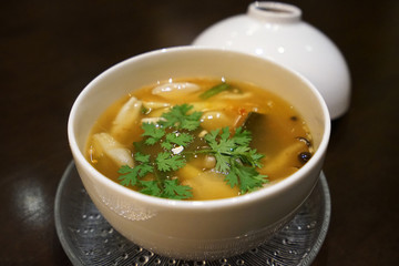 Close up ceramic bowl of Tom Yum- Thai style spicy broth soup made of chili paste and mushroom