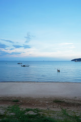Fototapeta na wymiar View of seascape with long tail boats, seashore sand and green island with cloudy blue sky- Chumphon,Thailand