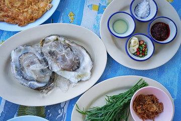 Close up fresh oyster served with Thai style dipping sauce, garlic and vegetables