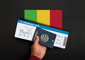 Hand holds passport and boarding pass with flag of Mali