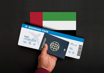 Hand holds passport and boarding pass with flag of United Arab Emirates