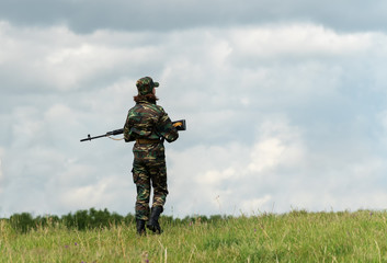 A woman in uniform with a rifle in the army patrolling the border area.