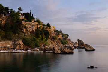 Fototapeta na wymiar Cliffside resort at dusk on Turkish Riviera at Antalya Kaleici Harbour Turkey