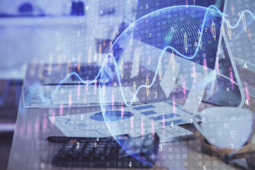 Double exposure of graph and financial info and work space with computer background. Concept of international online trading.