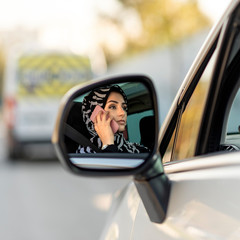 beautiful muslim woman talking by phone while driving	