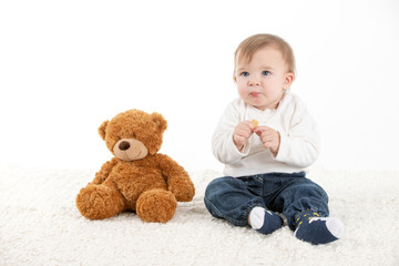 Baby eating with fingers with a teddy bear