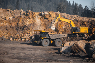 Open pit gold mine, big yellow mining truck moves ore
