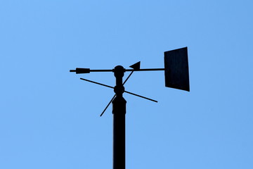 Silhouette of vintage retro weather vane instrument showing wind direction and arrow pointing...