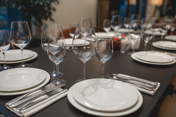 Empty Glasses, forks, knives, plates on a table in restaurant served for dinner