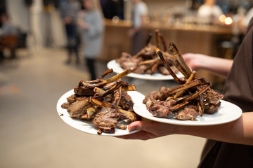fresh cooked lamb chops on plate being served by waiter
