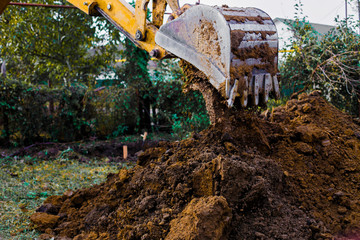 Backhoe loader working at construction site.Vehicle arm with bucket moving ground. Excavator works.  © Lomiso