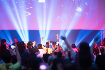 Rear view of crowd with arms outstretched at concert or seminar training in hall