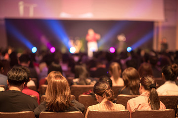 Speaker on the stage with Rear view of Audience in the conference hall or seminar meeting, business and education concept