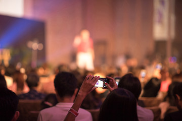 Audience using smart phone technology for take a photo and There is speaker standing in front of the room at the conference hall, Business and Entrepreneurship concept