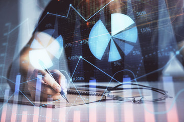 Multi exposure of woman's hands making notes with forex graph hologram. Concept of technical analysis.