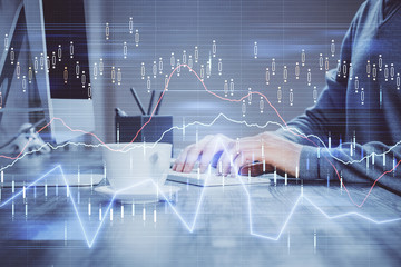 Multi exposure of graph with man typing on computer in office on background. Concept of hard work.